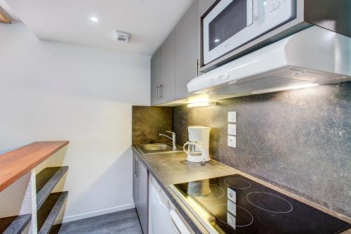a kitchen with a sink and a microwave at Vacancéole - Le Privilège in Germ