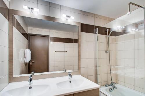 a bathroom with a sink and a mirror and a tub at Vacancéole - Le Privilège in Germ