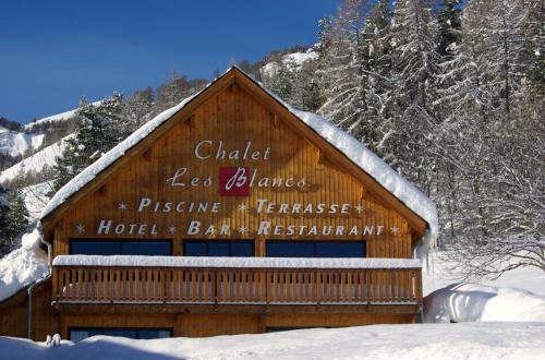 a building with a sign on it in the snow at Chalet Hôtel Les Blancs in Pra-Loup
