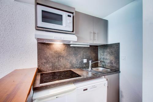 a kitchen with a stove and a microwave at Vacancéole - Le Privilège in Germ