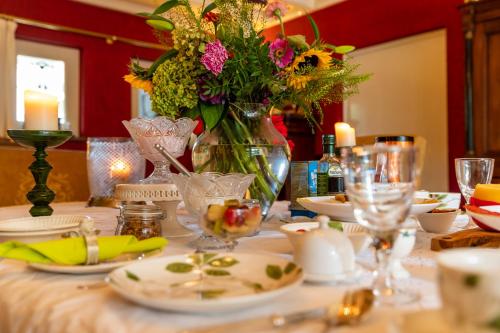 a table with a vase of flowers and plates on it at Beck's Bed and Breakfast in Kaatsheuvel