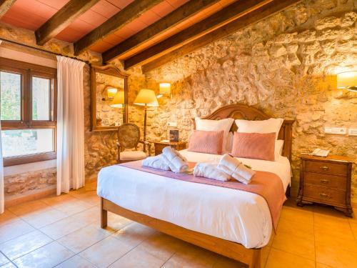 a bedroom with a large bed and a stone wall at Sa Bassa Rotja Ecoturisme in Porreres