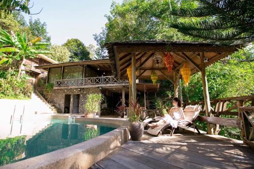 une femme assise sur une chaise à côté d'une piscine dans l'établissement Fig Tree Hills Resort (花果山度假村), à Bayan Lepas