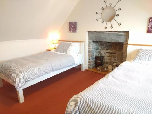 two beds in a room with a fireplace at Sandend Cottage in Banff