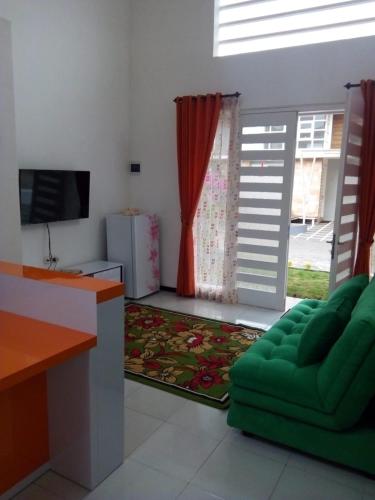 a living room with a green couch and a television at Vila Monex in Batu