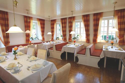 un restaurante con mesas y sillas blancas y ventanas en Haus Hildegunde, en Bad Füssing