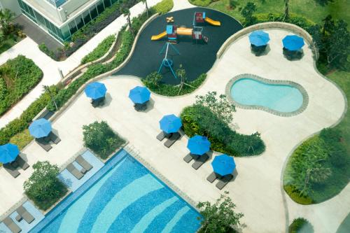 an overhead view of a resort pool with tables and blue umbrellas at Fraser Place Setiabudi Jakarta in Jakarta