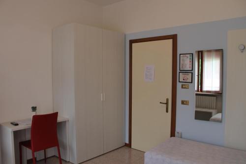 a room with a bed and a desk and a red chair at Hotel O'Scugnizzo 2 in Belluno