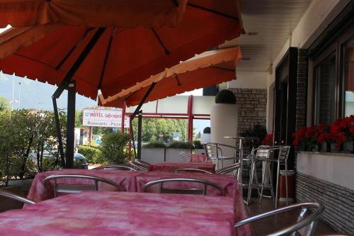 a restaurant with red tables and chairs with umbrellas at Hotel O'Scugnizzo 2 in Belluno