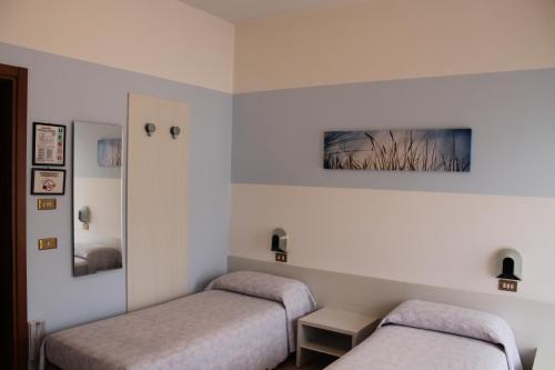 two beds in a room with white walls at Hotel O'Scugnizzo 2 in Belluno