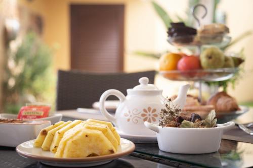une table avec des assiettes de nourriture et une théière dans l'établissement B&B Aurora Salentina, à Morciano di Leuca