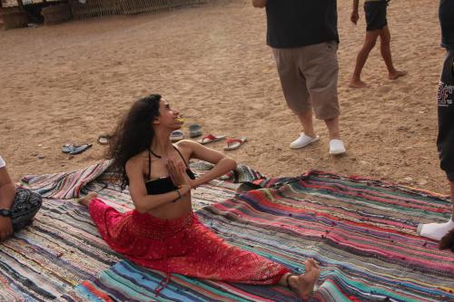 a woman sitting on a blanket on a beach at SakraTah Camp - eco friendly in Taba