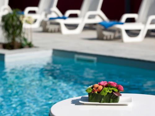 a small flower arrangement on a table next to a pool at Hotel Bikini in Rimini