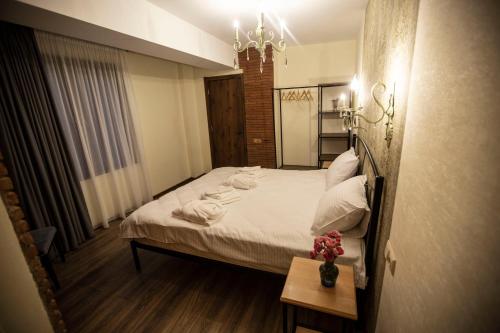 a bedroom with a bed with white sheets and pillows at Wine Hills in Tbilisi City