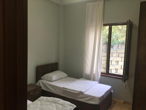 two beds in a small room with a window at Emerald House Gabala in Gabala