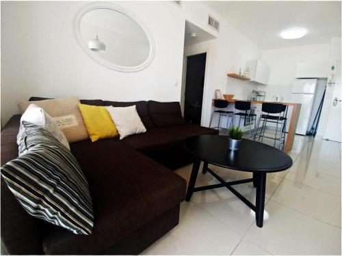 ein Wohnzimmer mit einem braunen Sofa und einem Tisch in der Unterkunft Koral Suite in Eilat