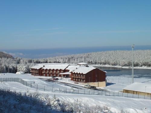 a building covered in snow next to a body of water at Fenerbahçe Serkan Acar Resort&Sports Topuk Yaylası in Dereceören