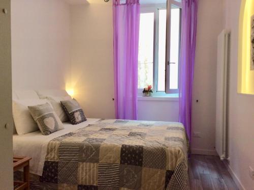 a bedroom with a bed with purple curtains and a window at Carpe Diem in Arco