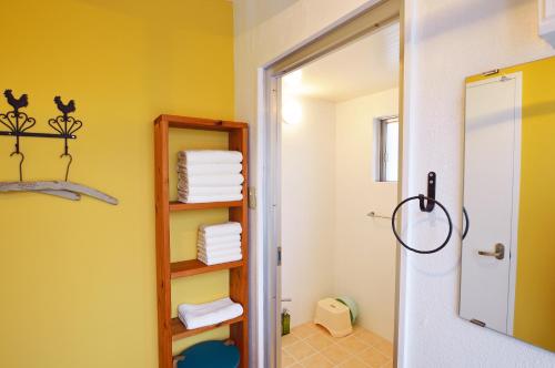 un bagno con pareti gialle, specchio e asciugamani di Douce a Ginowan