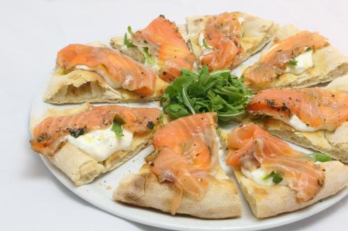 a white plate with a pizza with fish on it at City Guest House in Rome