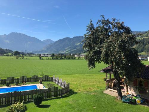 a house with a fence and a tree in a field at Urlaub am Bauernhof Rothof in Sankt Johann im Pongau