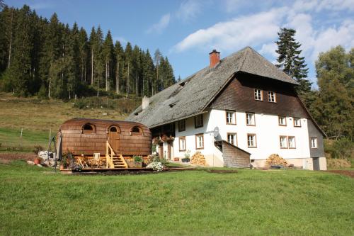 une grande maison blanche avec un toit en gambrel dans l'établissement Igluhut Tiny House Winterberghof, à Vöhrenbach