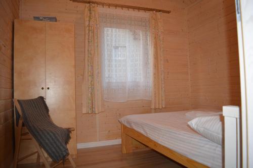 um pequeno quarto com uma cama e uma janela em RÓŻANY ZAKĄTEK em Zełwągi