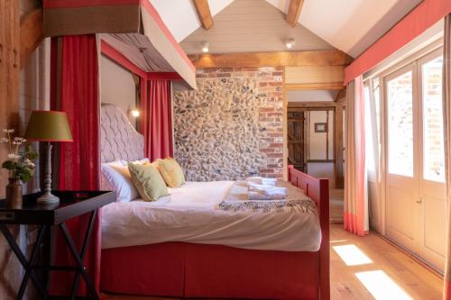 a bedroom with a red canopy bed with a brick wall at Retreat East in Ipswich