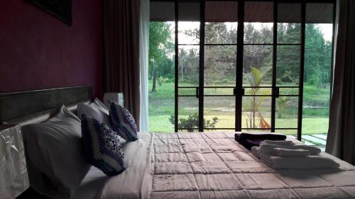 a bedroom with a large bed with a large window at Raintree Bangsak in Khao Lak