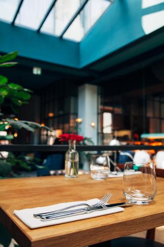 a wooden table with two glasses and a napkin at The Bank Hotel in Amsterdam