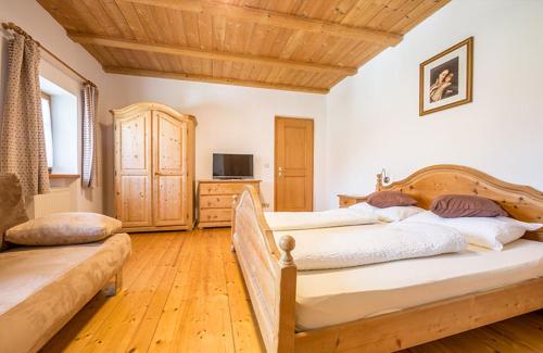 a bedroom with two beds and a wooden ceiling at Großflatscherhof in Brunico