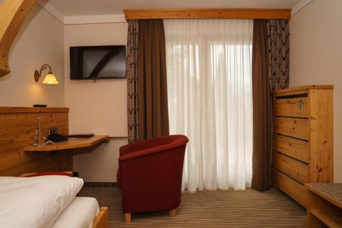 a hotel room with a bed and a chair at Landgasthof Zur Post in Schwangau