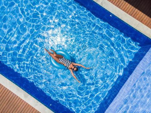 a person swimming in a pool on a blue raft at Bessa Beach Hotel in João Pessoa