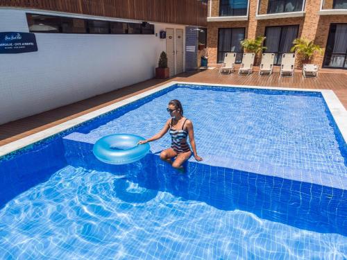 a woman in a swimming pool with a frisbee at Bessa Beach Hotel in João Pessoa