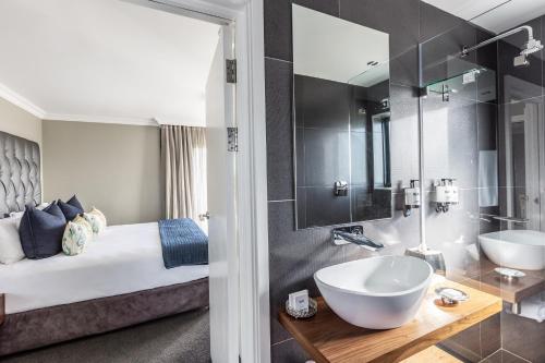 a bathroom with a bed and a sink and a mirror at Bliss Boutique Hotel in Cape Town