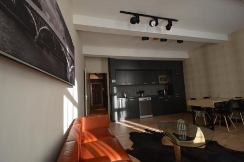 a living room with a couch and a table and a kitchen at Amosa Liège City Centre Hotel in Liège