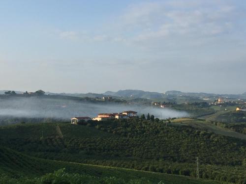 a foggy valley with a farm in the middle of a field at Cascina Baresane in Alba