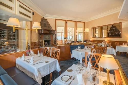 een restaurant met witte tafels en stoelen en een open haard bij Hotel Mirabeau, BW Signature Collection, Lausanne in Lausanne