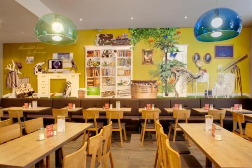 a restaurant with wooden tables and chairs and yellow walls at MEININGER Hotel Berlin Mitte in Berlin