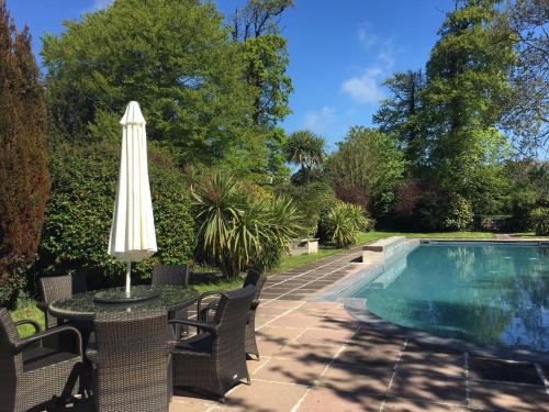 a table with an umbrella next to a swimming pool at Durrant House Hotel in Bideford