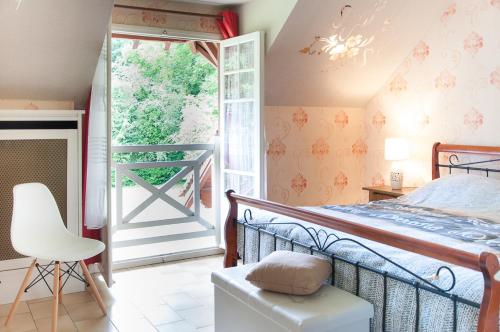 a bedroom with a bed and a window and a chair at Maison Lalongère in Longueville