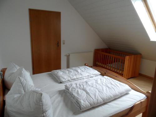 a bedroom with a bed with white sheets and a crib at Landsitz Riekenshof in Horumersiel in Wangerland