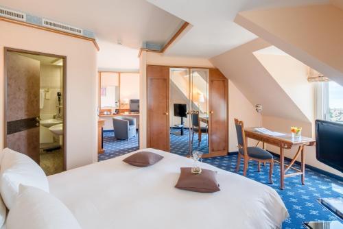 a hotel room with a bed, table and chairs at Best Western Plus Hotel Mirabeau in Lausanne