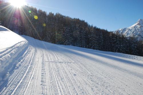 a snow covered road with the sun in the background at Residence La Tana del Ghiro in Bardonecchia