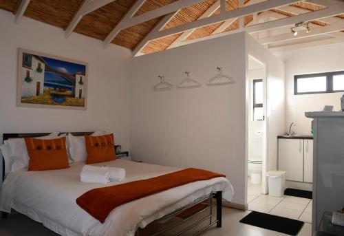 a bedroom with a large white bed with orange pillows at Bradclin House in Cape Town