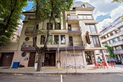 a tall building with tables and chairs on a street at Hotel Perfect in Varna City