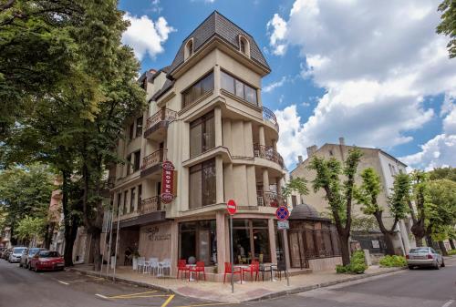 a tall building with red chairs in front of it at Hotel Perfect in Varna City