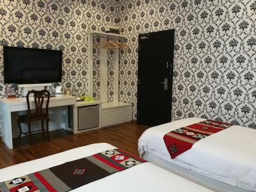 a room with two beds and a desk and a television at Jonker Boutique Hotel in Malacca