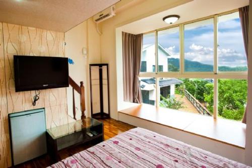 a bedroom with a bed and a large window at Miaoli Sanyi Bo Wu Guan Homestay in Sanyi