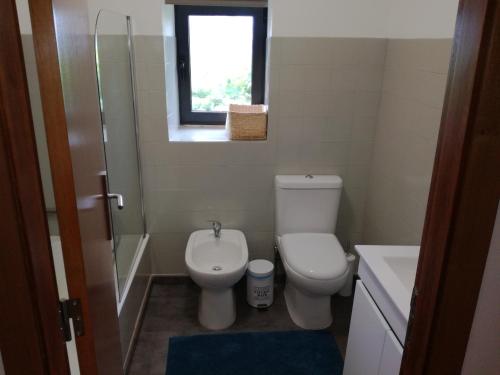 a bathroom with a toilet and a sink and a window at Casa de Paulus - Gerês in Geres